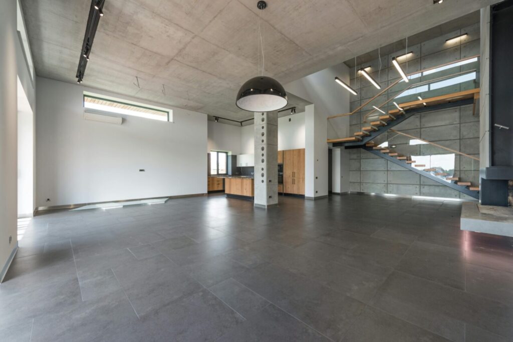 Open-concept industrial loft space featuring modern staircase, minimalist architecture, and ample natural light.